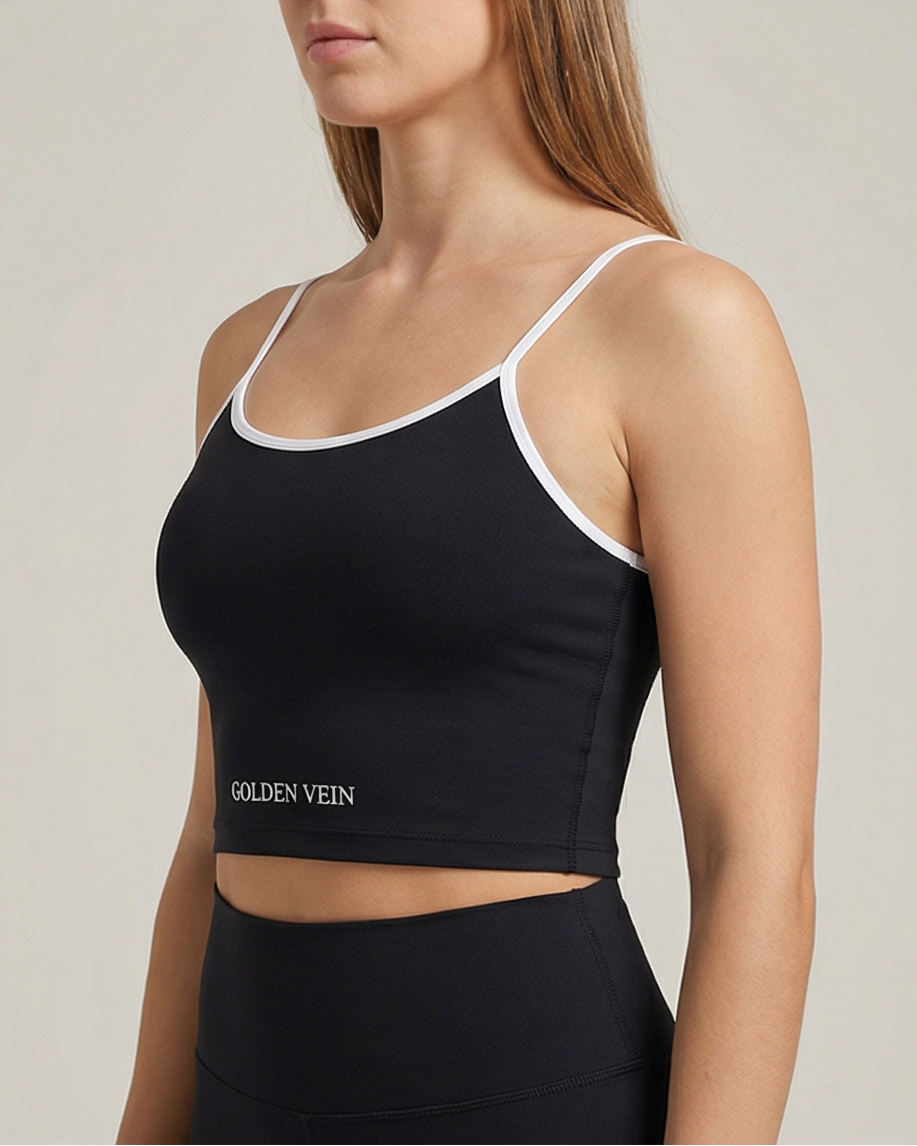 Schwarzes Golden Vein Essential Crop Top aus weichem Stretchmaterial, getragen von einem sportlichen weiblichen Model in Studioaufnahme; klare Silhouette und minimalistisches Design. 45 Grad Ansicht.