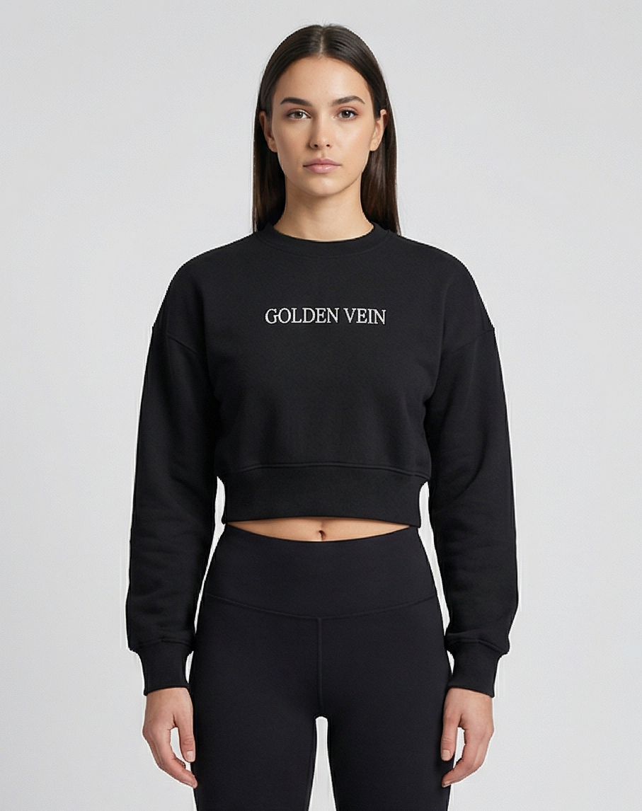 Schwarzer Golden Vein Cropped Sweater, frontale Studioaufnahme an einem weiblichen Model; weiche Stoffstruktur, kurze Passform und minimalistischer Logo-Print.