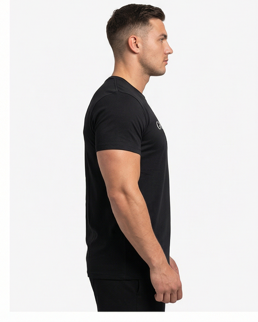 Schwarzes GV Essential Shirt, seitliche Studioansicht eines männlichen Models; Fokus auf Silhouette und Ärmelpassform.