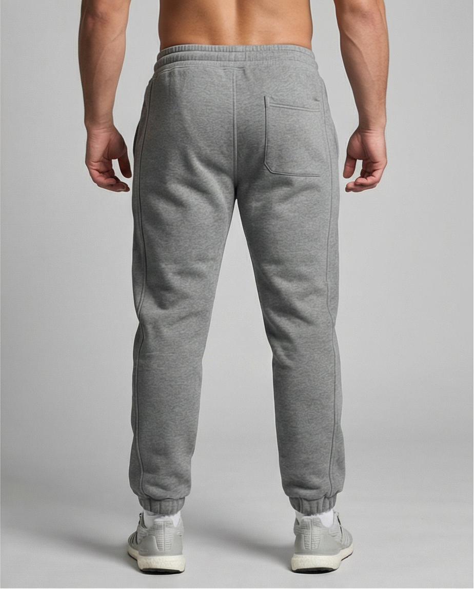 Graue GV Essential Sweatpants, Rückansicht an männlichem Fitness-Model; sichtbare Taschenform und glatter Stoffverlauf.
