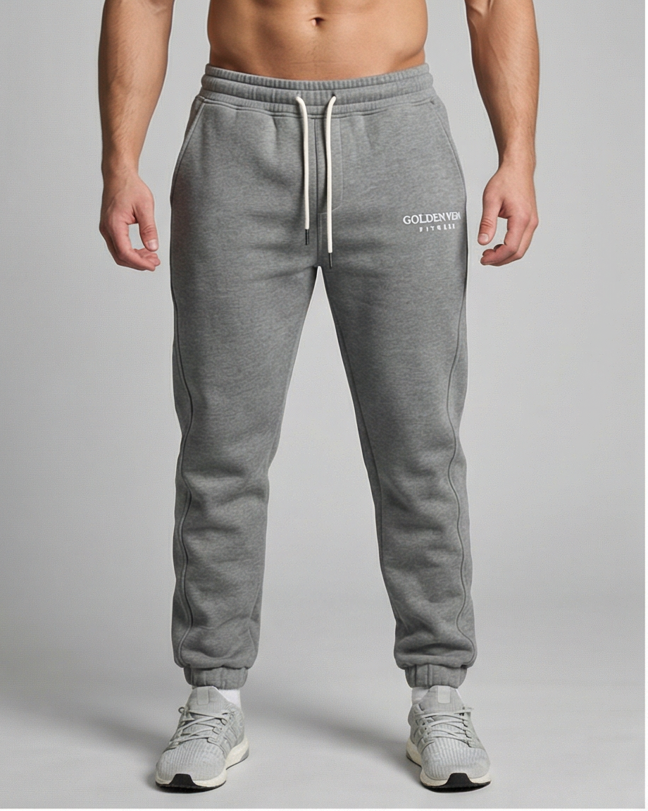 Graue GV Essential Sweatpants, frontale Studioaufnahme an einem männlichen Fitness-Model; elastischer Bund, gerade Silhouette, weiche Baumwollstruktur.