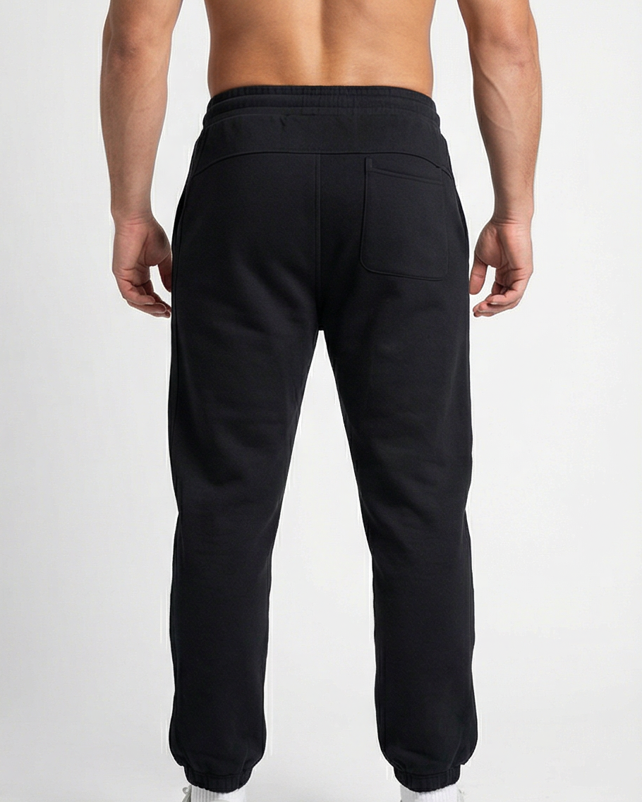 Schwarze GV Essential Sweatpants, Rückansicht an männlichem Fitness-Model; glatter Stoffverlauf und sichtbare Taschenform.