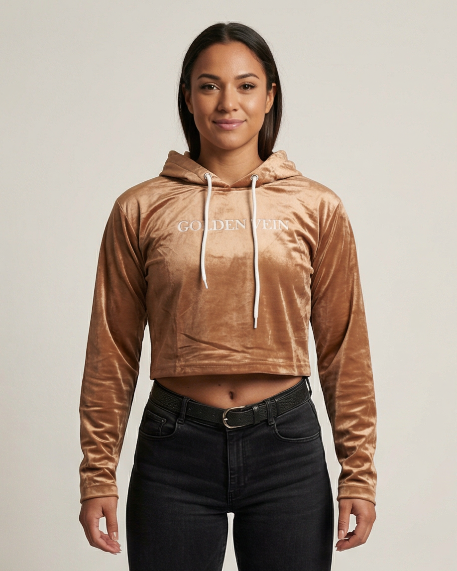 Golden Vein Velvet Cropped Hoodie in karamellbraun, frontale Studioaufnahme an einem weiblichen Model; weiche Samtstruktur, cropped Passform und dezenter Logo-Print.